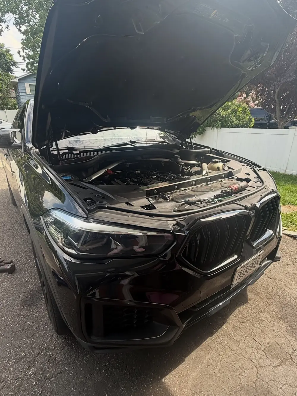 Black BMW X6 with the hood open for engine work