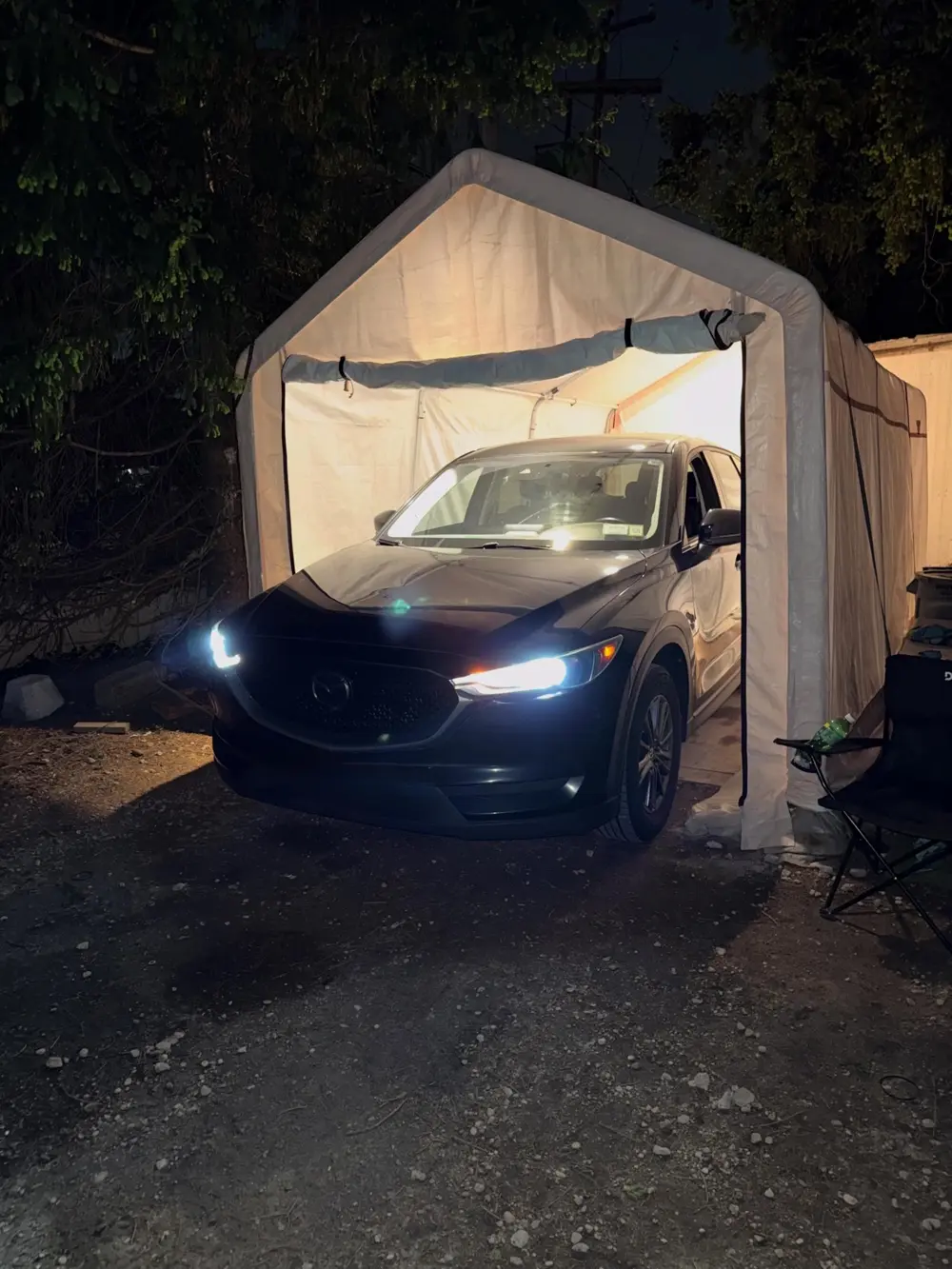 Black Mazda CX-5 with its headlights on at night